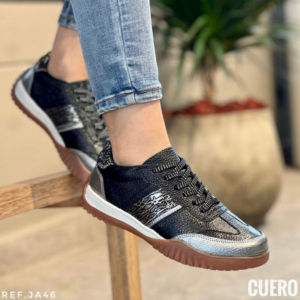 Bolichero de cuero negro para mujer con detalles plateados, suela café y media suela blanca, visto de perfil con jeans azules.